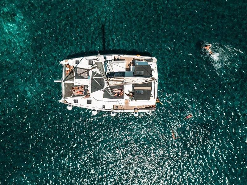 A catamaran seen from above on clear water inside the caldera