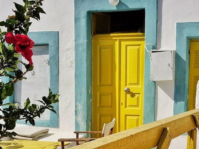 A yellow door and bougainvillea in a whitewashed island lane