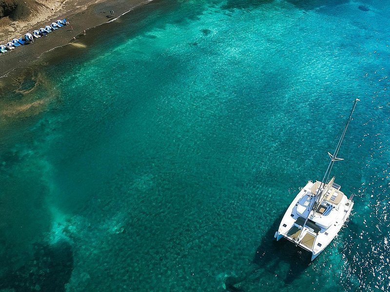 A catamaran anchored over turquoise shallows off the south coast