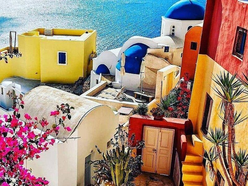 Ochre and red houses with bougainvillea on the caldera rim at Oia