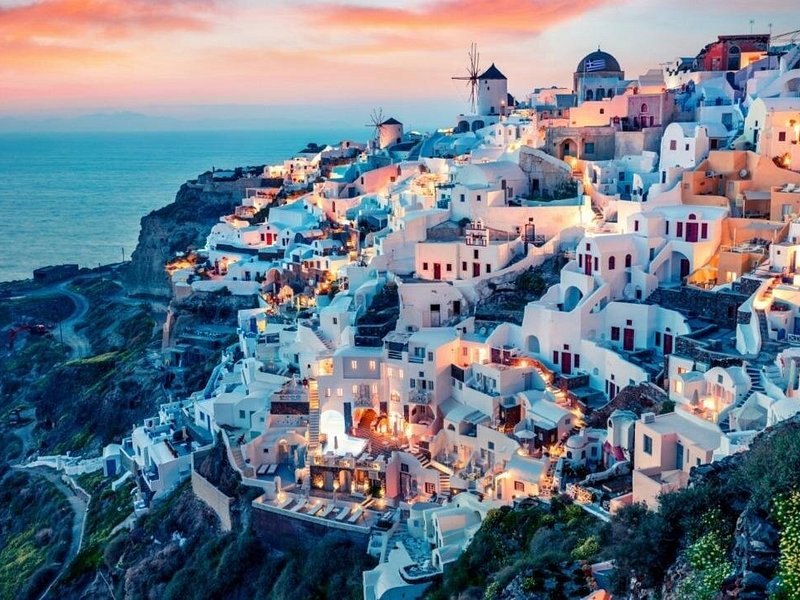 Oia and its windmill after sunset, the village lights coming on