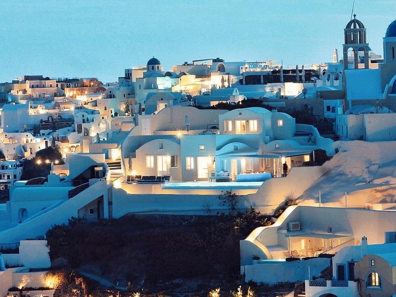 Oia's cave houses lit from within at blue hour