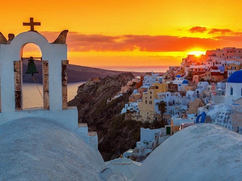 Oia framed through a whitewashed bell arch as the sun goes down