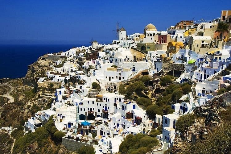Oia from above, the whole village strung along the caldera rim
