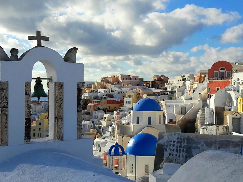 Oia seen through the arch of a whitewashed bell gable