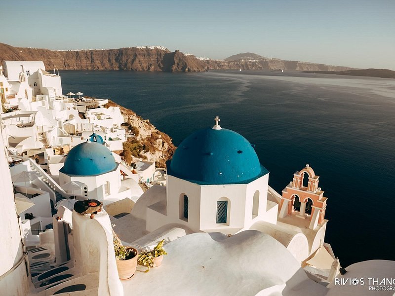 The domes of Oia standing above the red and black caldera cliffs