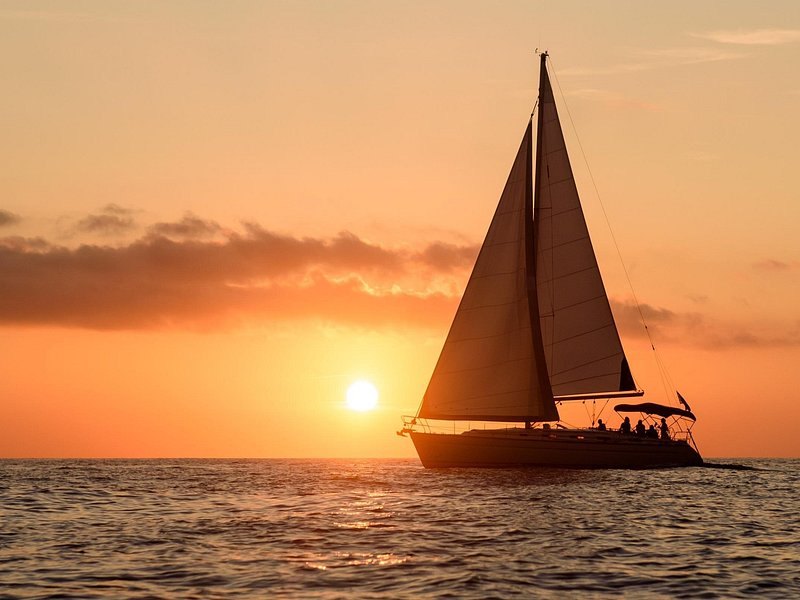 A yacht under sail on the Aegean as the sun drops behind Thirasia